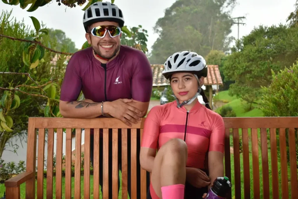 Pareja de ciclistas con jerseys personalizados vino y coral - NICKO Deportes